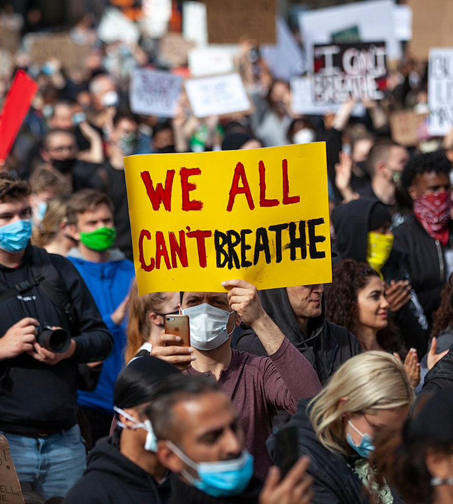 man holding a "We All Can't Breathe" sign during a protest