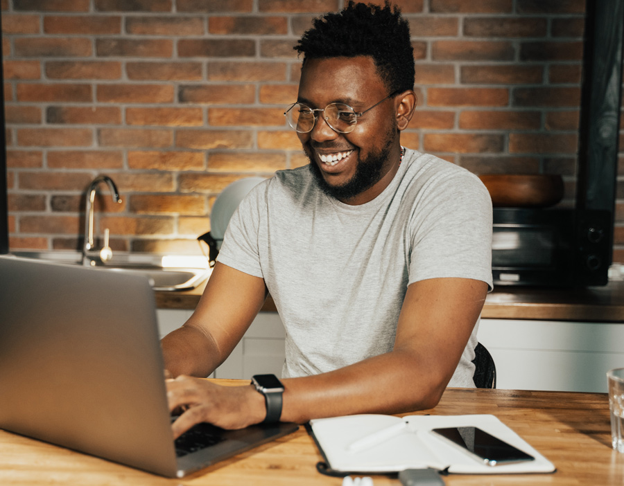 Man smiling while using a laptop