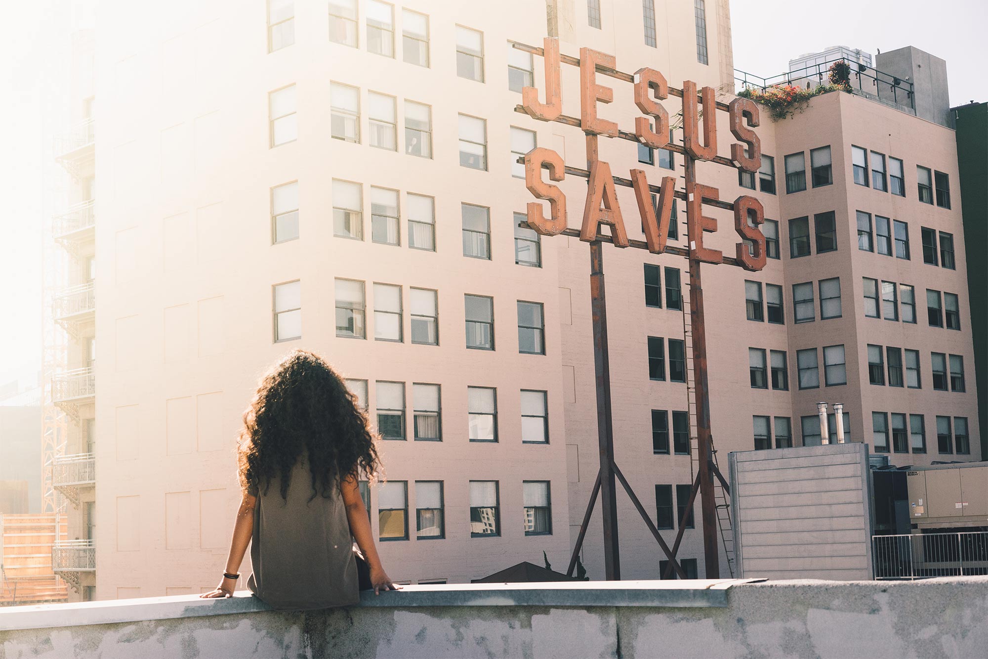woman on rooftop with Jesus Saves sign