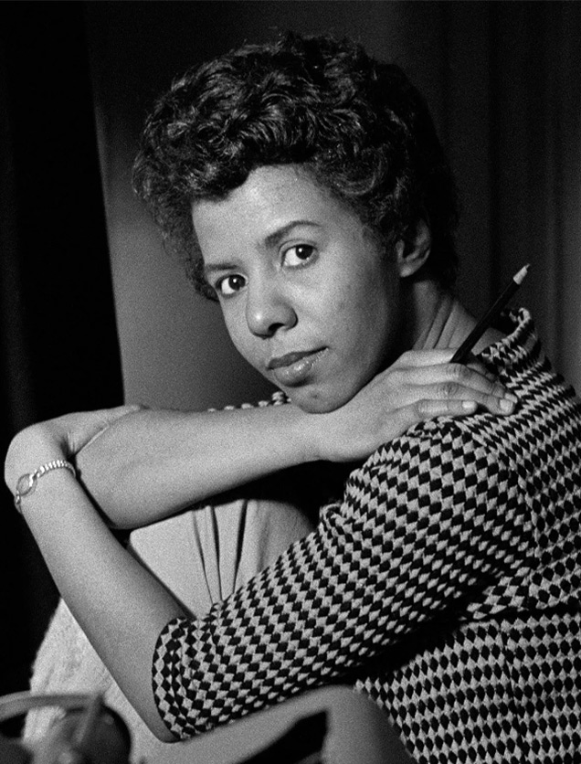 Lorraine Hansberry turned sideways and looking at the camera with her head propped on her arm