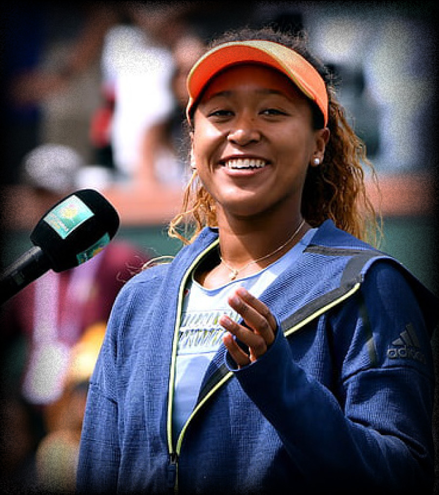 Naomi Osaka at a podium smiling