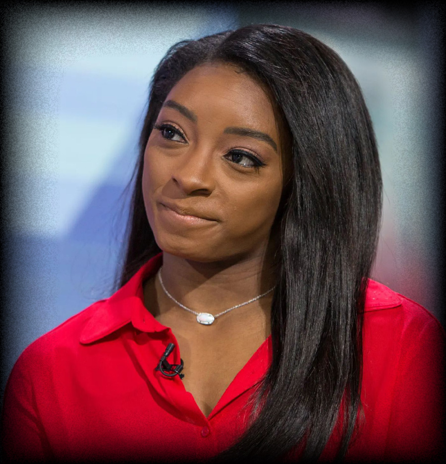 Simone Biles smiling in red button up shirt