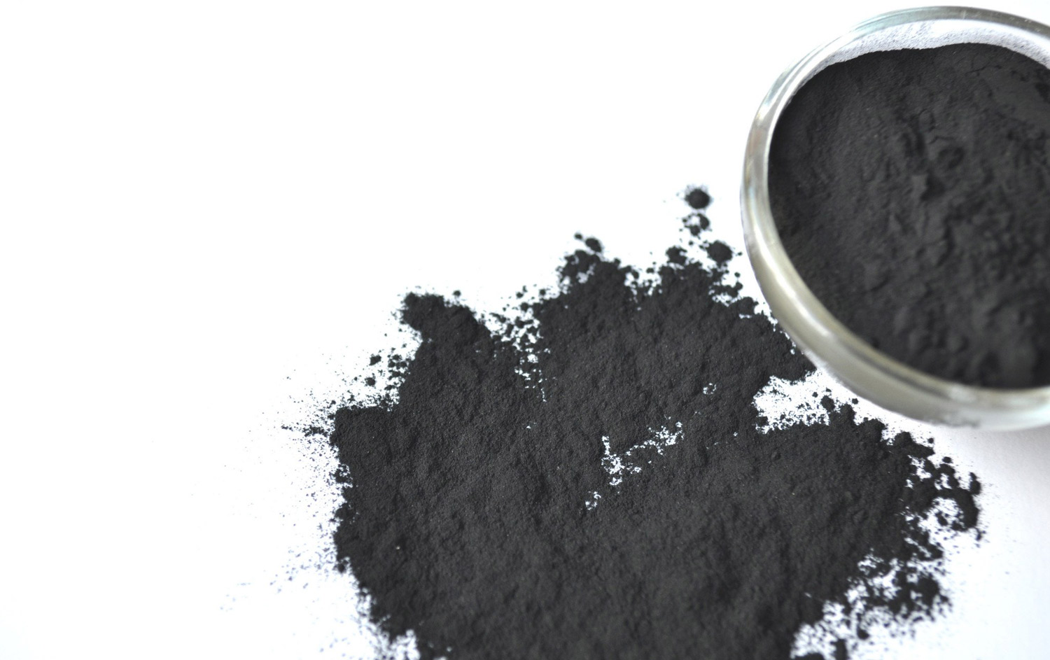 activated charcoal in a glass bowl and on a white surface