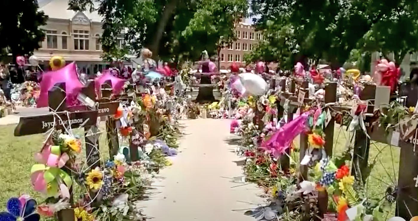 a walkway lined with crosses covered with flowers and balloons
