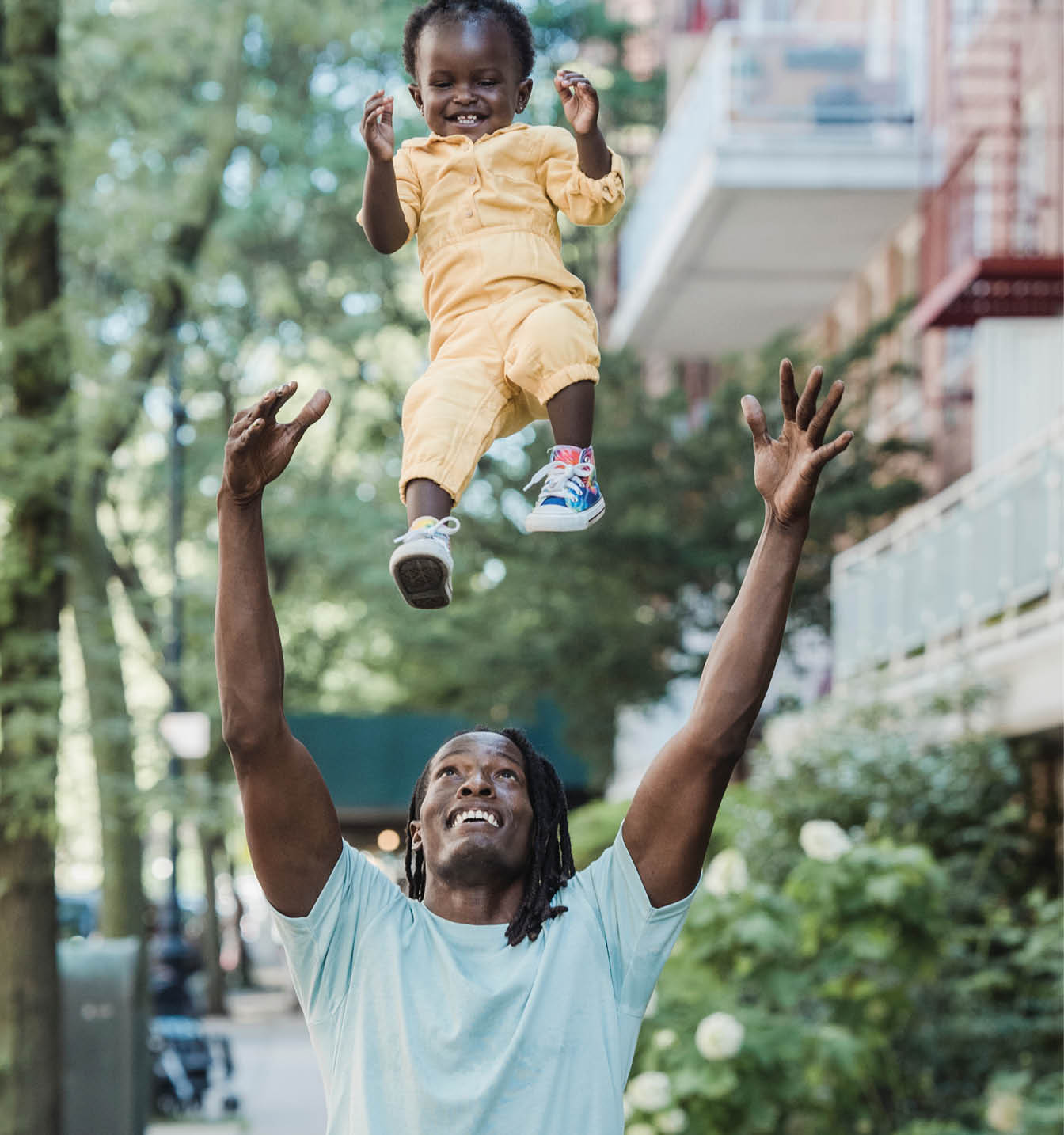 man throwing his laughing child in the air playfully smiling