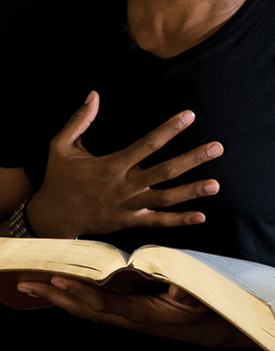 Close up of hand on chest and open book