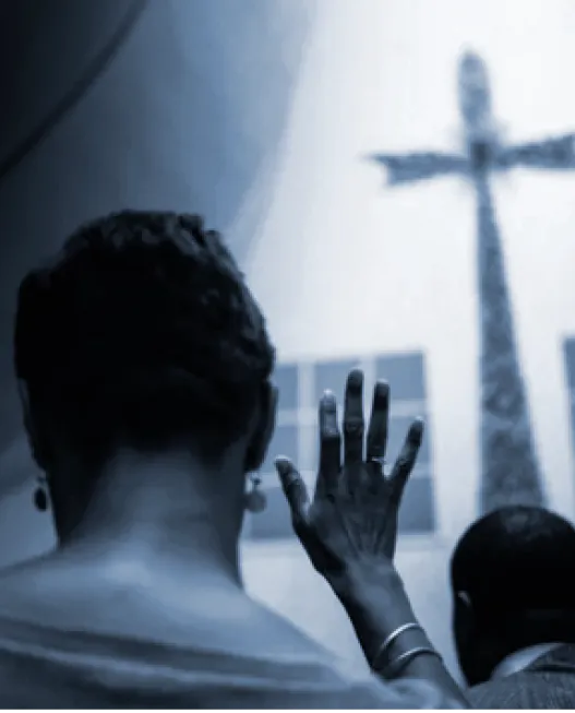 back of woman praying with cross in background