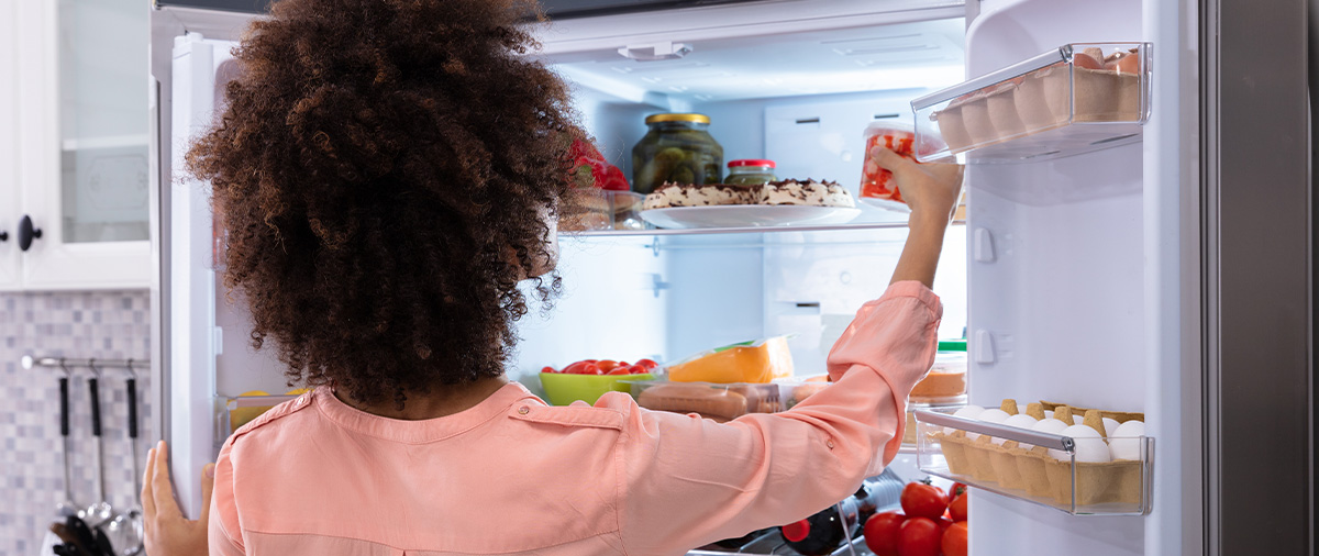 woman in pink shirt taking strawberries out of a fridge