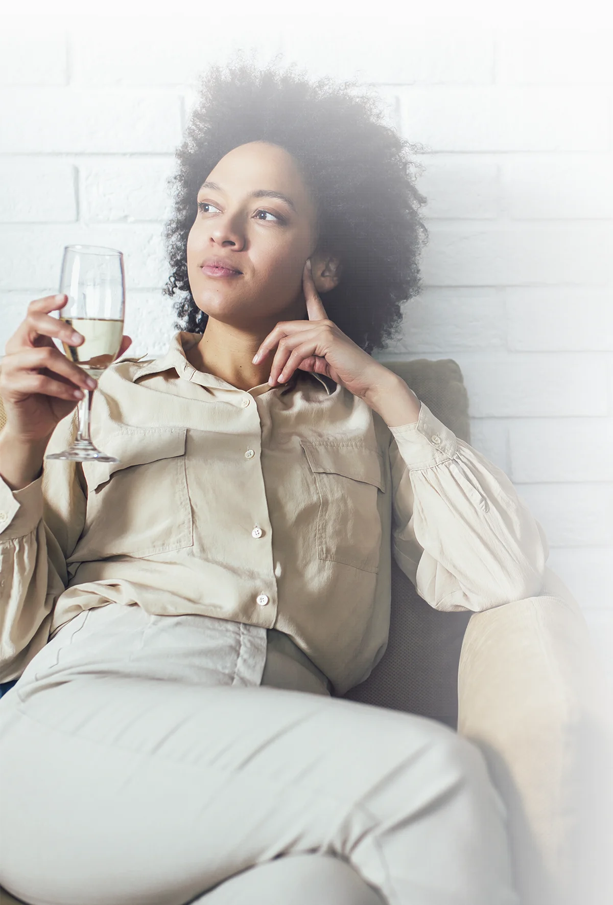 woman sitting crossed-legged on a sofa and holding a wine glass