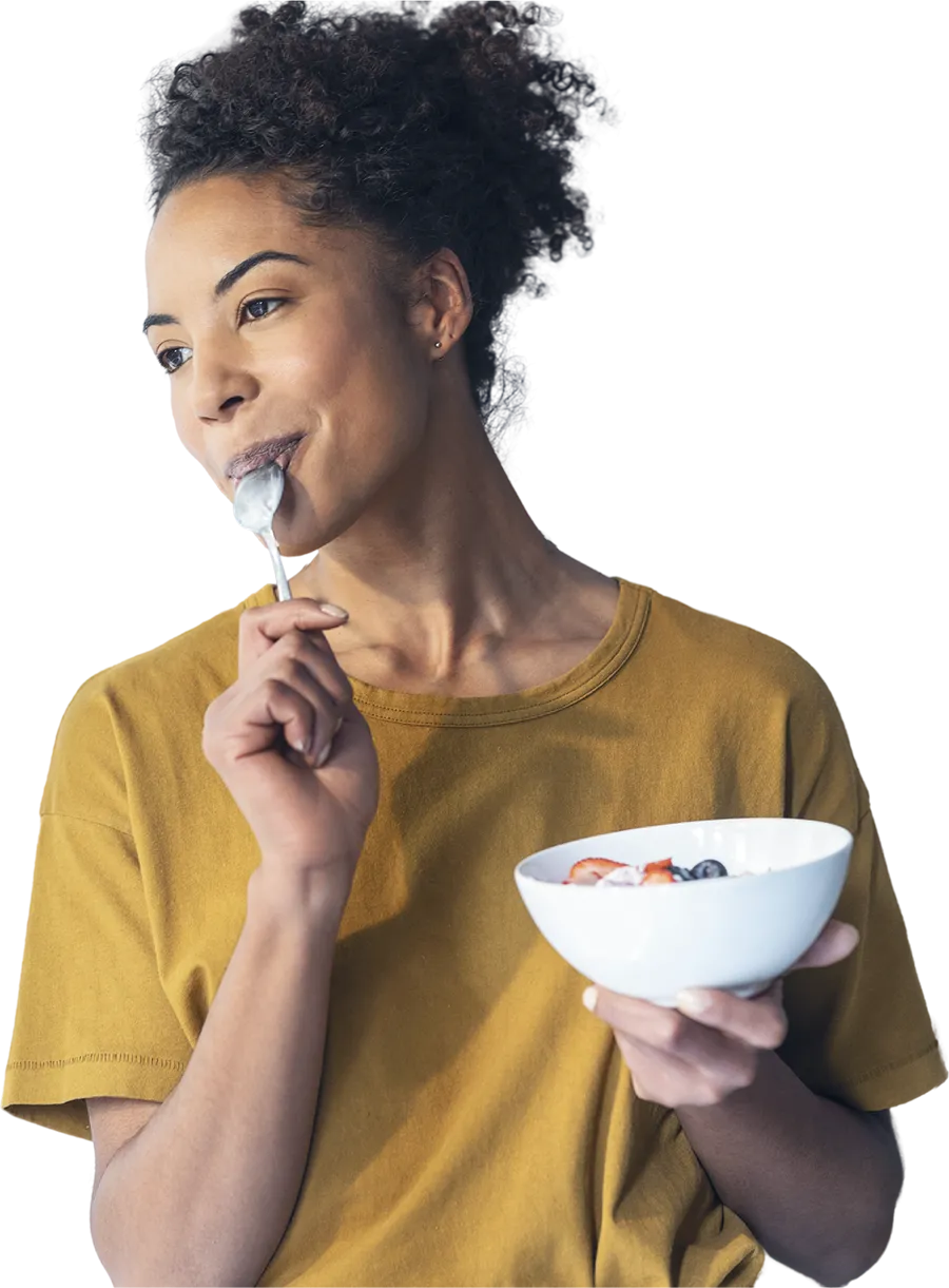 woman wearing a yellow shirt eating cereal from a bowl