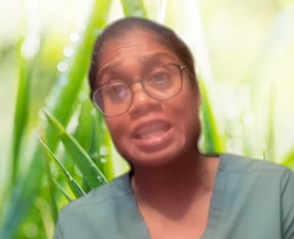 Headshot of a woman in green scrubs with a leafy background.