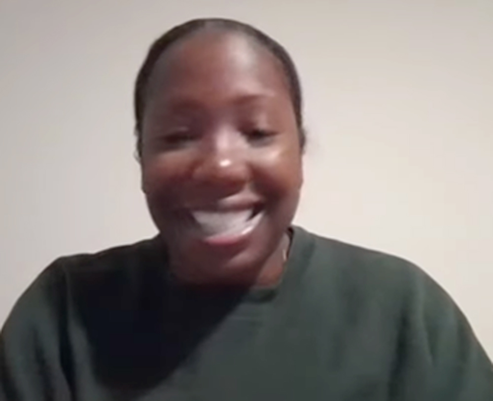 Headshot of a smiling Black woman in a dark green sweatshirt.