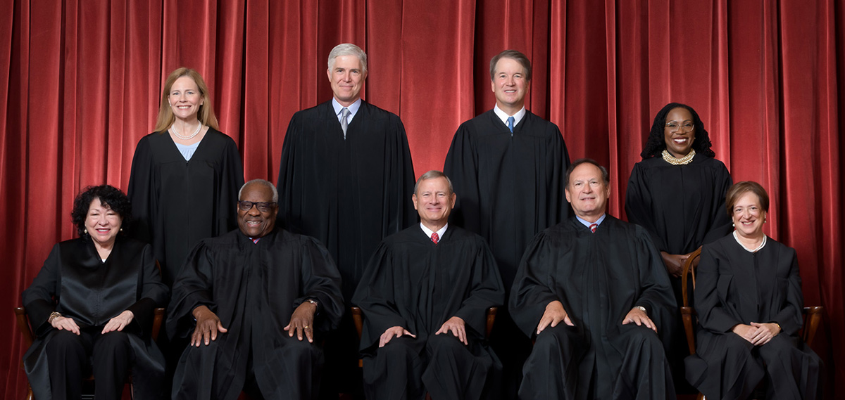 The official group portrait of the nine justices of the United States Supreme Court, posed in two rows against a background of heavy red drapery