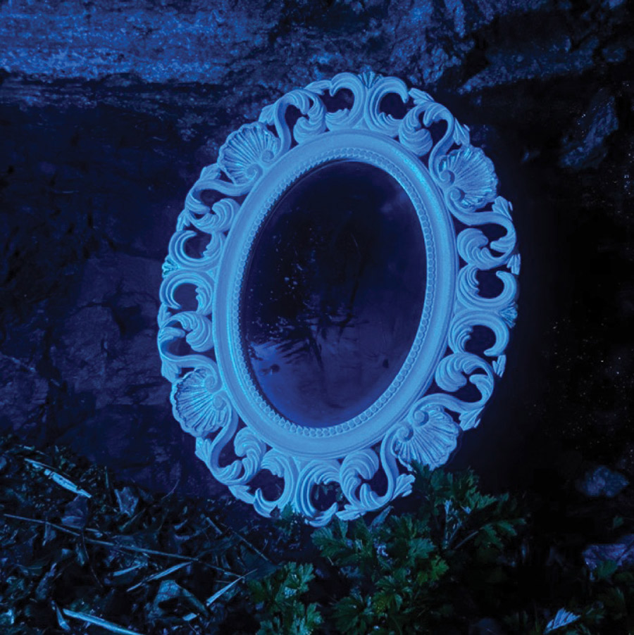 An ornate oval mirror reflecting a dark scene under an eerie blue light.