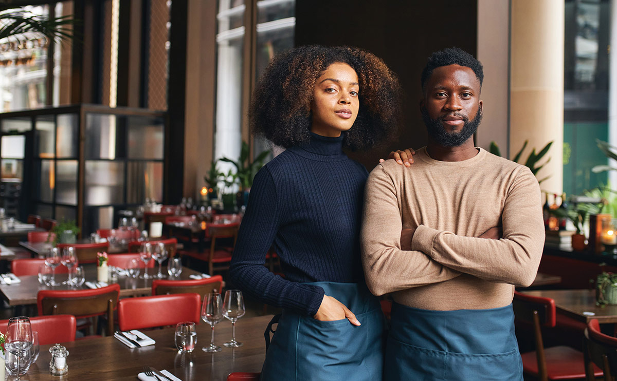 A man and woman posing beside each other in a restaurant