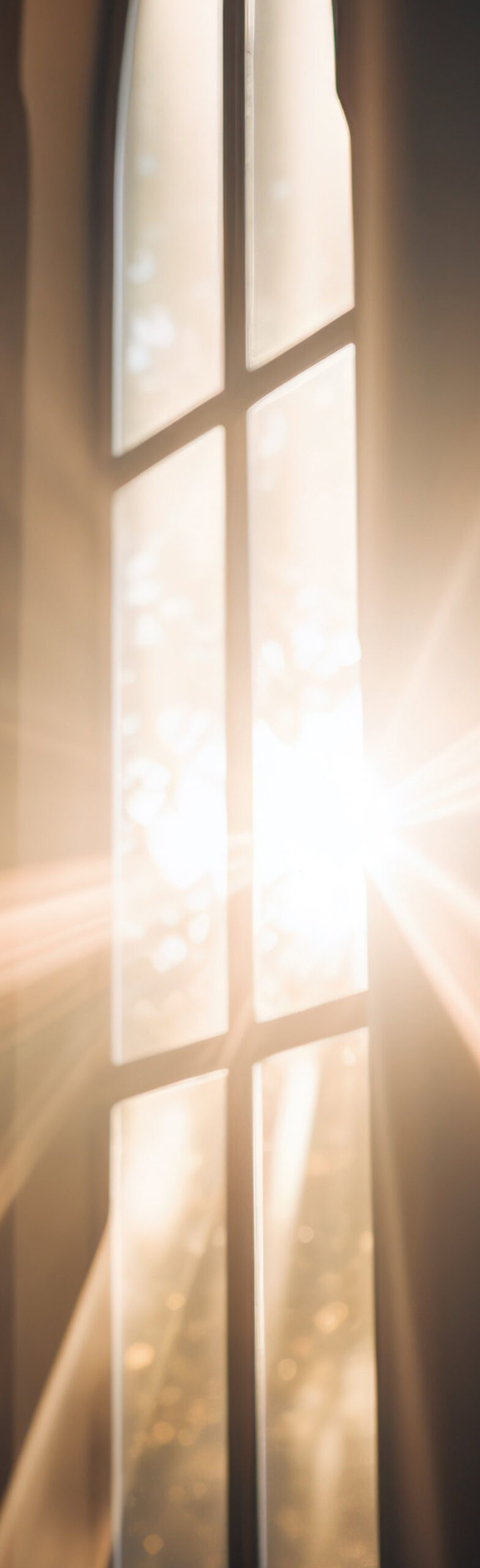 Bright morning sunlight streaming in through a tall, narrow glass pane window, creating dramatic light rays and a warm glow.