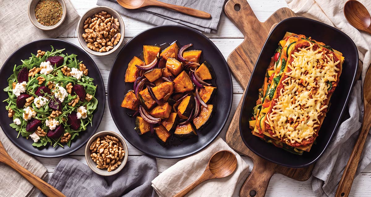 Flat lay view of vegan spread with beet salad, roasted squash, and vegetable lasagna.